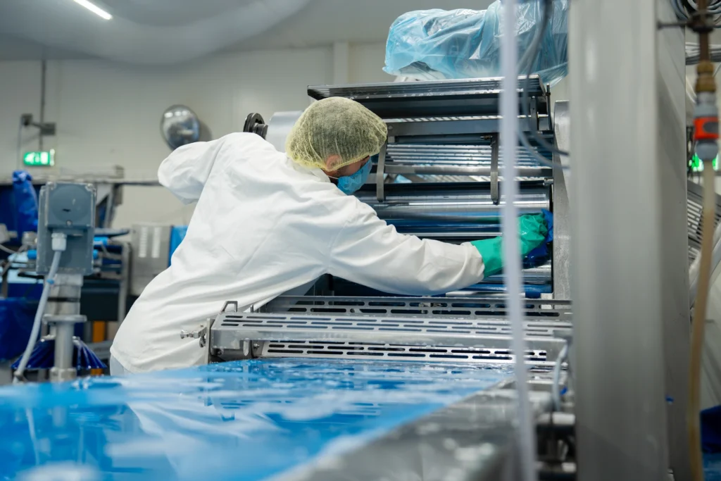 Medewerker in hygiënekleding reinigt een koelruimte