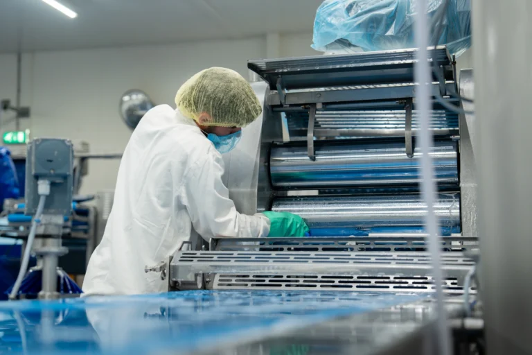 Medewerker in hygiënekleding reinigt een productielijn