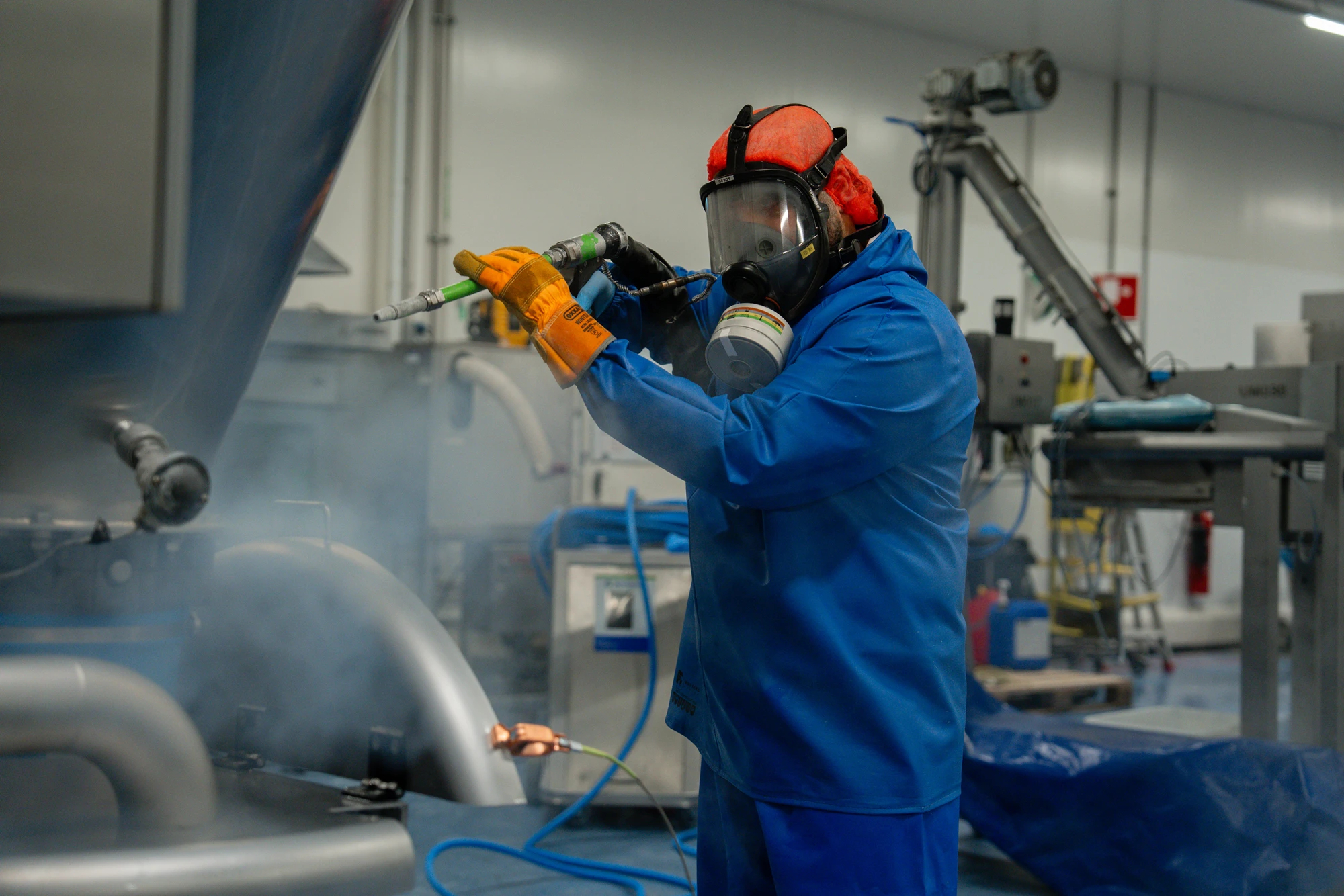 Medewerker met gehoorbescherming reinigt een machine