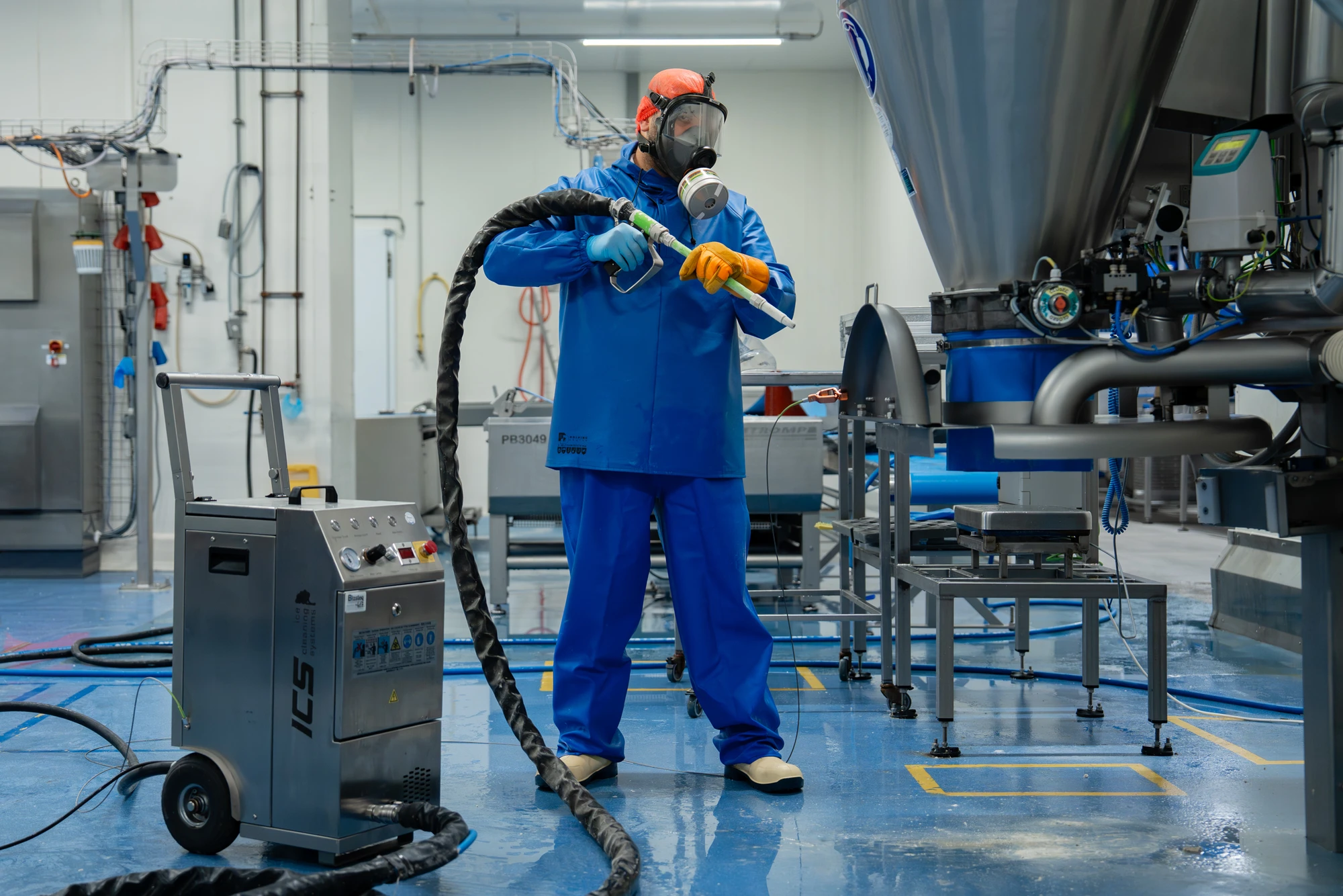 Medewerker reinigt een industriële installatie met een stofzuiger