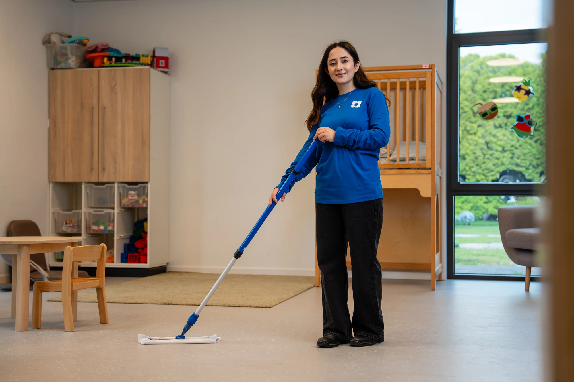 Schoonmaakster dweilt de vloer van een lokaal