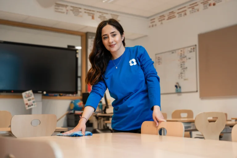 Schoonmaakster maakt een tafel schoon in een vergaderruimte